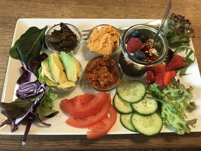 Veganes Four-Seasons-Frühstück mit Avocado, Hummus, Gemüse und Obst
