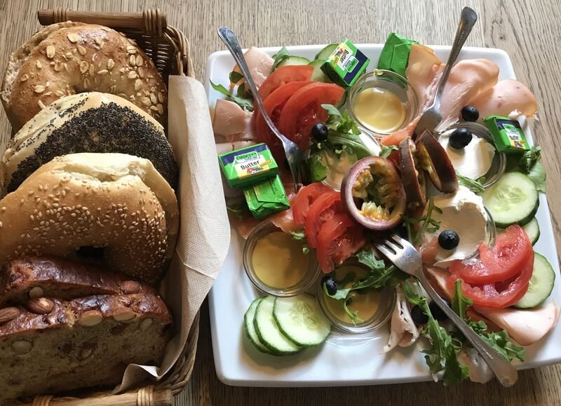 Großes Bagel-Frühstück mit Aufschnitt, Gemüse, Ei und Aufstrichen
