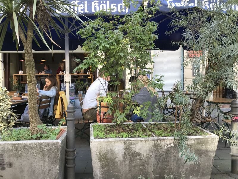Das cafecafe von der Aachener Straße aus gesehen, mit Pflanzen vor dem Eingang