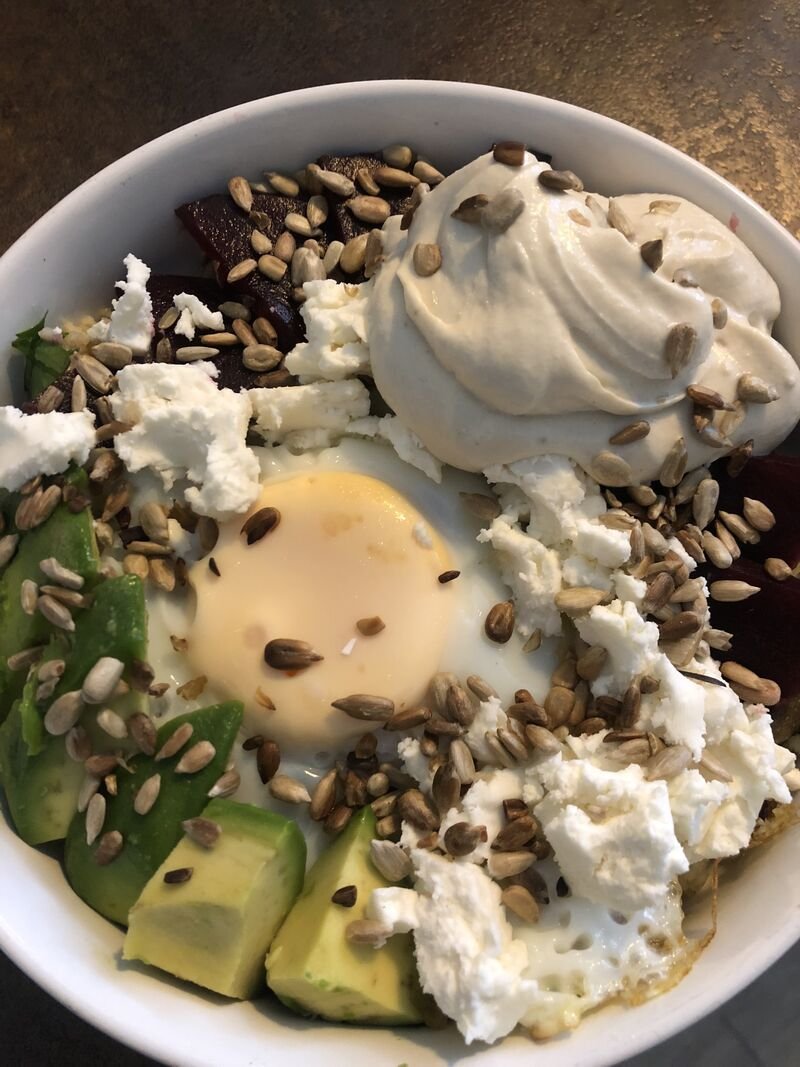 Bowl mit Avocado, pochiertem Ei, Kernen und Frischkäse