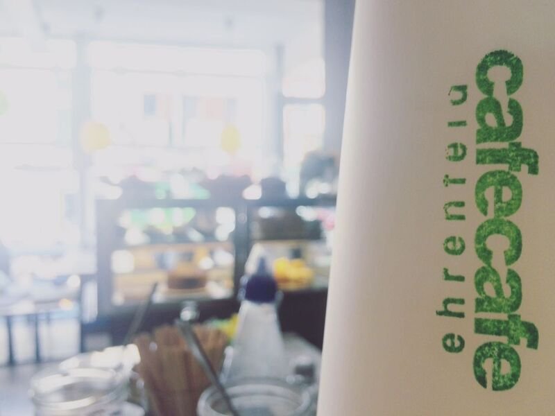 Coffee-to-go-Becher mit grünem Aufdruck cafecafe ehrenfeld
