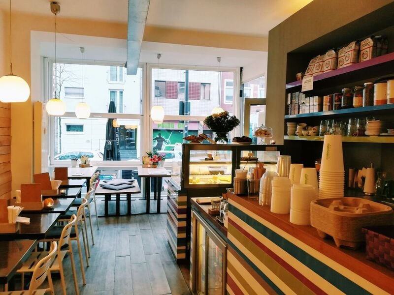Heller Gastraum des cafecafe Ehrenfeld mit Holztresen, Regalen und Fensterfront zur Venloer Straße